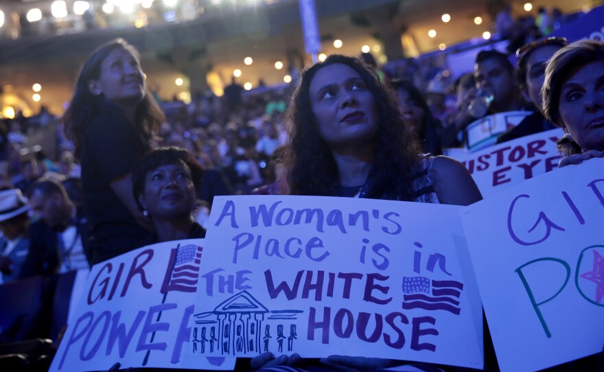 Delegates hold up signs on the convention floor in support of Clinton.