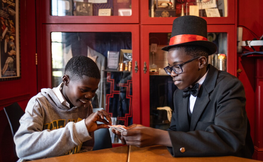 Themba Van der Westhuizen, 12, practices a magic trick on a schoolmate at the College of Magic. Van der Westhuizen says he enjoys impressing friends and family with his tricks and that learning to become a magician has boosted his self-confidence.