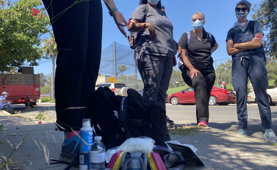 Christina Kelley gestures to her pack of supplies as ANA/C San Diego Regional Task Force members Nicole Ward, Trisha Weers and Danisha Jenkins look on, June 10, 2020.