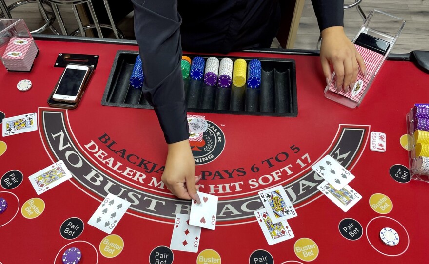 Michelle Fernandez, an instructor at the Millennium Casino Academy, demonstrates how table games are played in California’s card rooms. If Proposition 26 passes, they could be forced to change the way they do business or shut down.