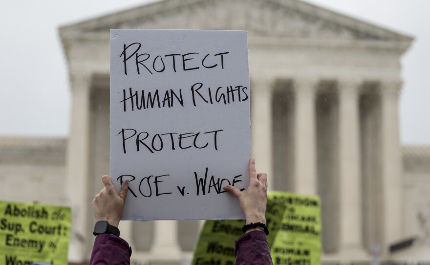 An abortion-rights protester holds up a sign during a demonstration in front of the Supreme Court on Saturday in Washington, D.C. Less than a week since the leaked draft of the Court's potential decision to overturn <em>Roe v. Wade,</em> protesters on both sides of the abortion debate continue to demonstrate in front of the building which has been fortified by a temporary fence.