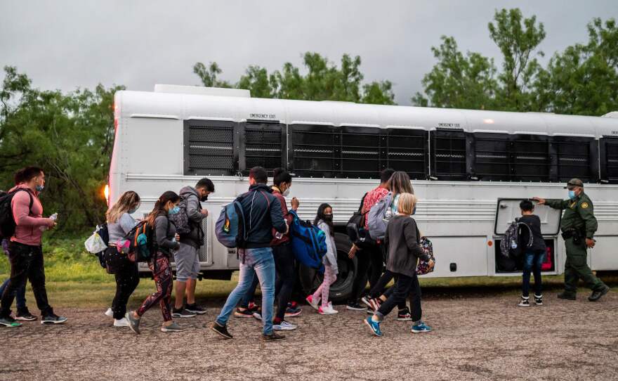 Migrants make their way toward a bus after being apprehended near the border between Mexico and the United States in Del Rio, Texas, on Sunday.