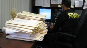 San Diego County Probation Officer Gonzalo Mendez works beside a stack of probation case files.