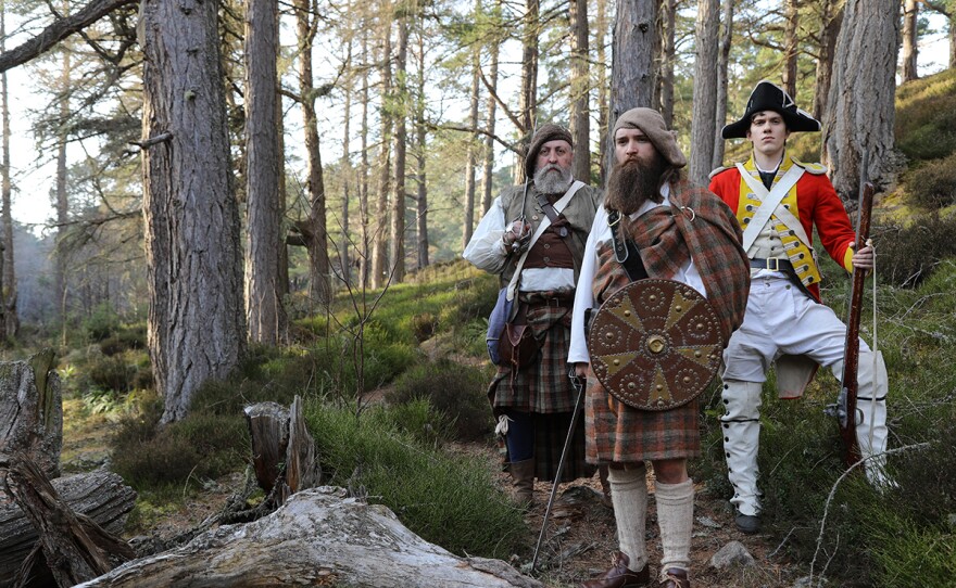 Drama reconstruction of Jacobites Rob Roy and his father Donald McGregor, and an English government trooper standing in the forest. Mar Lodge Estate, Scotland.