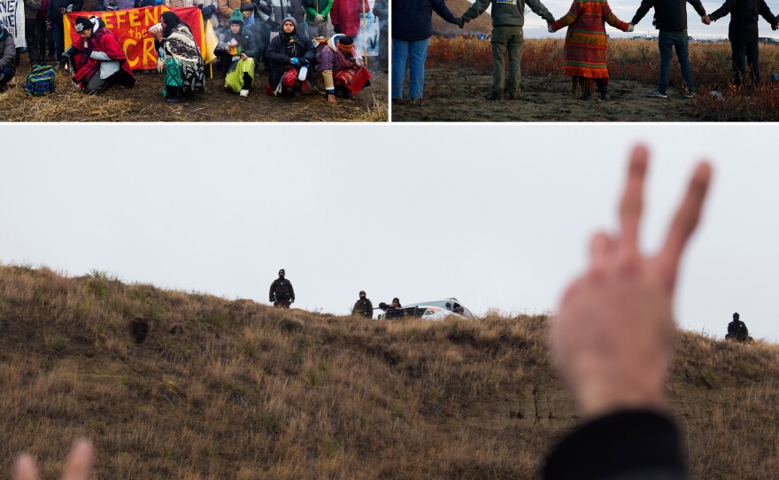 "Water protectors" join hands in prayer during a peaceful protest as police line a hill on Turtle Island.