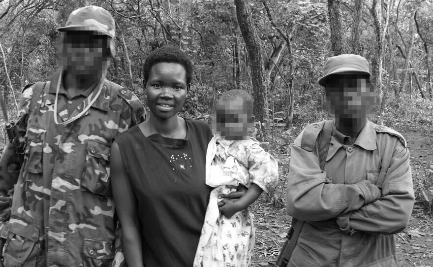 The picture was taken in 2006 in the Democratic Republic of Congo, after Evelyn Amony was rescued. Holding her youngest daughter, she was at a meeting to negotiate with members of the Lord's Resistance Army. The two men, who had also been abducted, are her relatives. The faces of the men and baby are blurred to protect their identities.