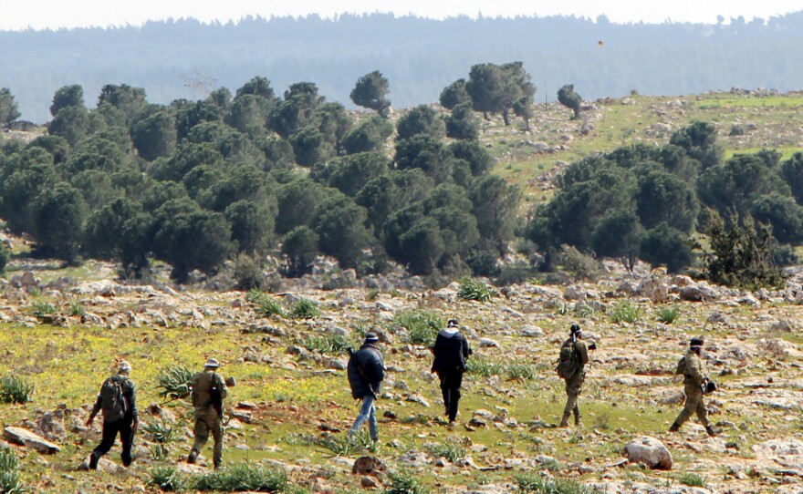 Fighters with the Turkish-backed Free Syrian Army advance through a field southeast of Afrin on Tuesday. Ankara and its allies among the Syrian rebels said Tuesday they have surrounded the Kurdish-held Syrian border town.
