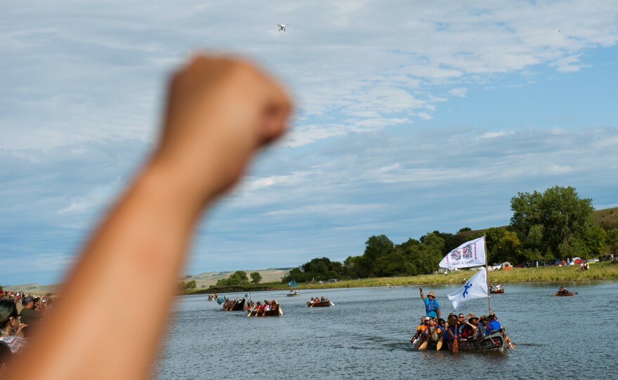 People raise their fists in solidarity as canoes arrive at a protest camp that sprang up to demonstrate against the pipeline. The canoe flotilla had representatives of tribes from across the Pacific Northwest, who had navigated the Missouri River from Bismarck to Cannon Ball to show their support.