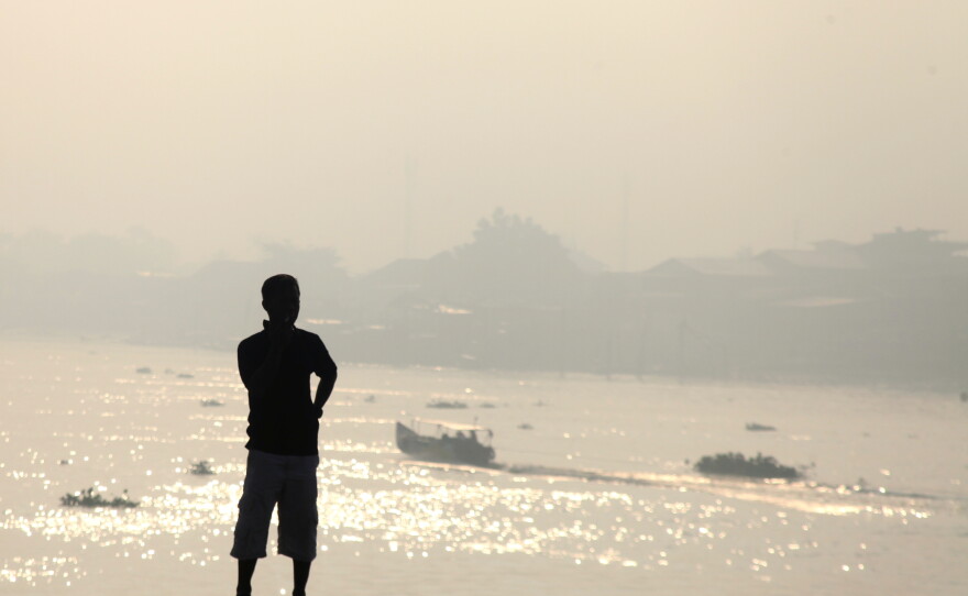 A man is silhouetted against the haze from wildfires that blankets Musi River in Palembang, South Sumatra, Indonesia, Sunday, Aug. 23, 2026.