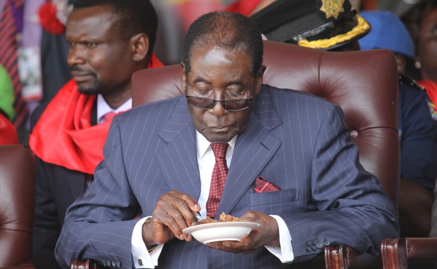 Zimbabwean President Robert Mugabe eats his cake during Saturday's celebrations to mark his 92nd birthday. Mugabe appears to have no plans to step down as feuding over his successors threatens to tear Zimbabwe's ruling party apart.