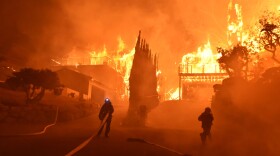 In this photo provided by the Ventura County Fire Department, firefighters work to put out a blaze burning homes early Tuesday, Dec. 5, 2017, in Ventura, Calif. 