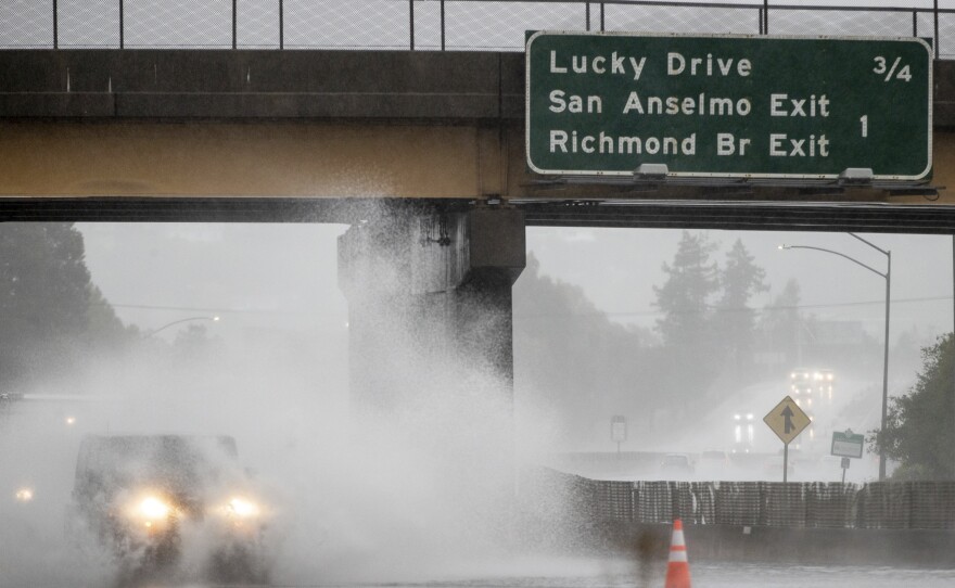 A car drives on Highway 101, which is partially flooded in Corte Madera, Calif., on Sunday.