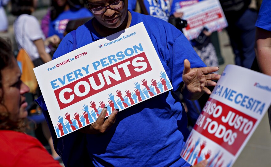 A demonstrator hands out a sign about the 2020 census outside the U.S. Supreme Court in Washington, D.C., in 2019. The Census Bureau is projecting the first set of census numbers won't be ready until February, Trump administration attorneys told a federal judge on Monday.