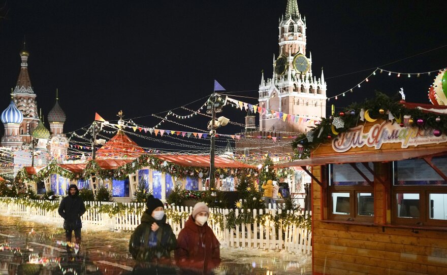 People walk past a market set up in Red Square with St. Basil's Cathedral to the left and the Spasskaya Tower on the right in Moscow on Monday.