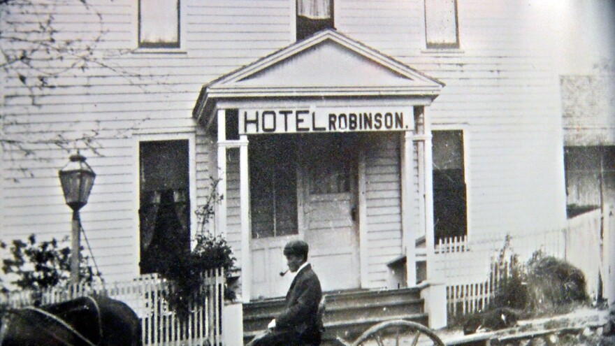 An undated photo of a man riding a horse and buggy in front of the Hotel Robinson on display at the African Diaspora Museum and Research Center, Feb. 10, 2023.