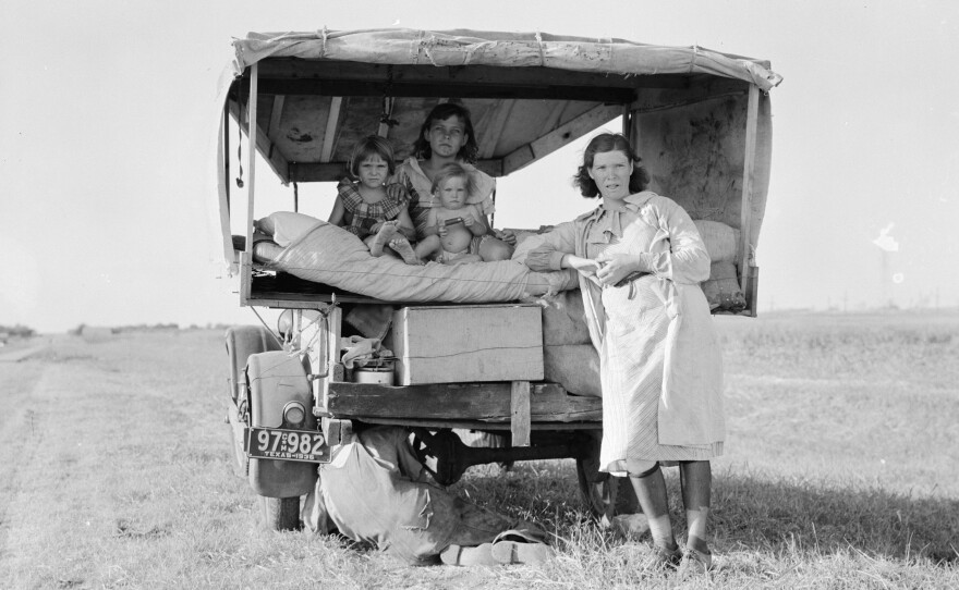 A family traveling between Dallas and Austin, Texas. "The people have left their home and connections in South Texas, and hope to reach the Arkansas Delta for work in the cotton fields," Lang wrote in her notes. "Penniless people. No food and three gallons of gas in the tank. The father is trying to repair a tire. Three children. Father says, 'It's tough but life's tough anyway you take it.' "