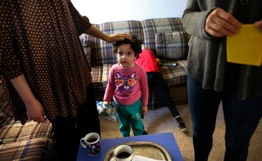 Fields (right) visits with Asmaa Dawoud, a refugee from Syria, while her daughter Dana looks on.