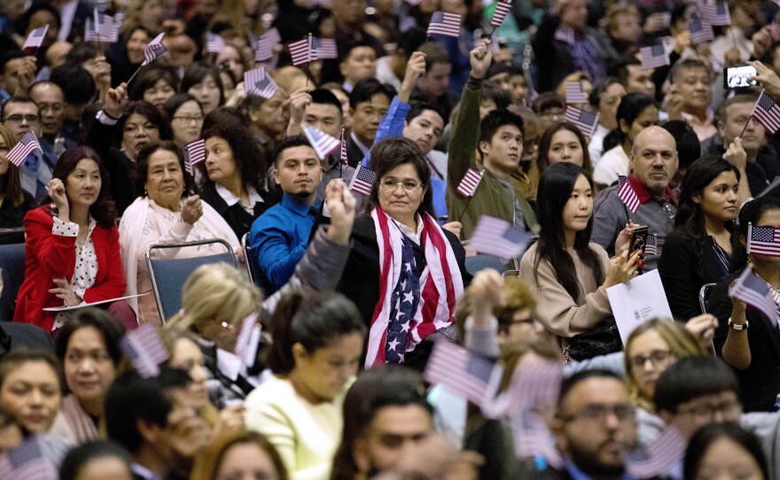 People wave U.S. flags during a 2017 naturalization ceremony at the Los Angeles Convention Center.