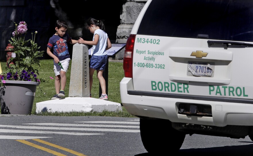 In this Wednesday, July 11, 2018 photo, two children, visiting the Haskell Library with their grandmother from Venezuela, play on the border pillar, as they circle back and forth between the United States and Canada under the watchful eye of a U.S. Border Patrol agent, seated in a vehicle, in Derby Line, Vt.