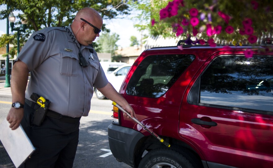 A traffic enforcement officer chalks tires in Arvada, Colo., in 2014. Physically marking a tire without a warrant is a violation of the Fourth Amendment, a federal appeals court ruled.