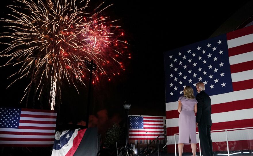 Jill and Joe Biden, wearing face masks, watch fireworks outside the Chase Center in Wilmington, Del., after Biden's acceptance speech for the Democratic presidential nomination.