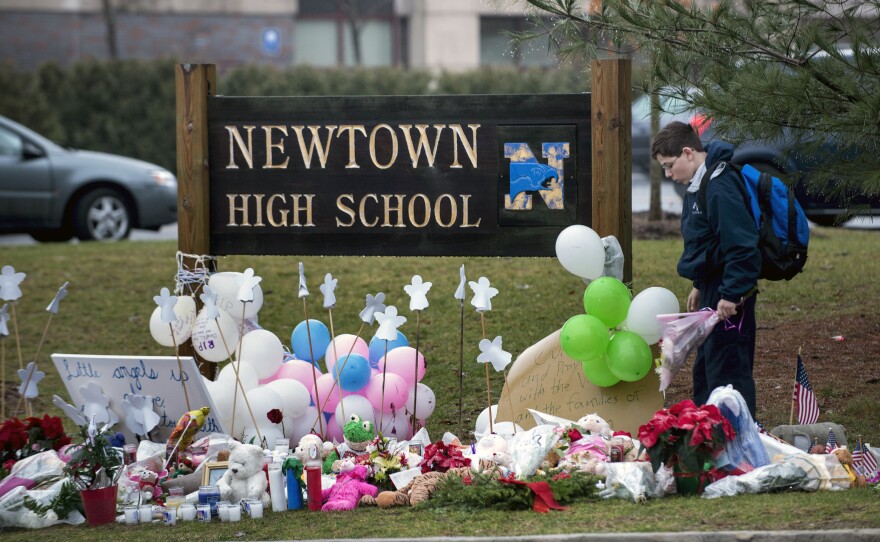 A student looks for a place to leave flowers at a makeshift memorial for the victims of the Sandy Hook Elementary School shooting at the entrance of Newtown High School on Tuesday in Newtown, Conn.