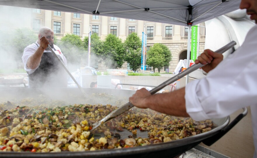 Chefs cook vegetables that will be added to a giant, 7-foot-wide platter of paella. The dish, made from produce diverted from the dump, was served up as part of a free feast for 5,000 in Washington, D.C., Wednesday to raise awareness about food waste.