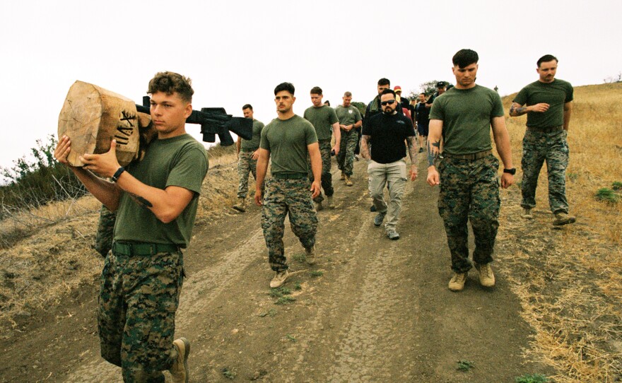 Marines of the 1st Battalion, 5th Marines hiking at Camp Pendleton with one of Anthony’s battlefield cross carvings.