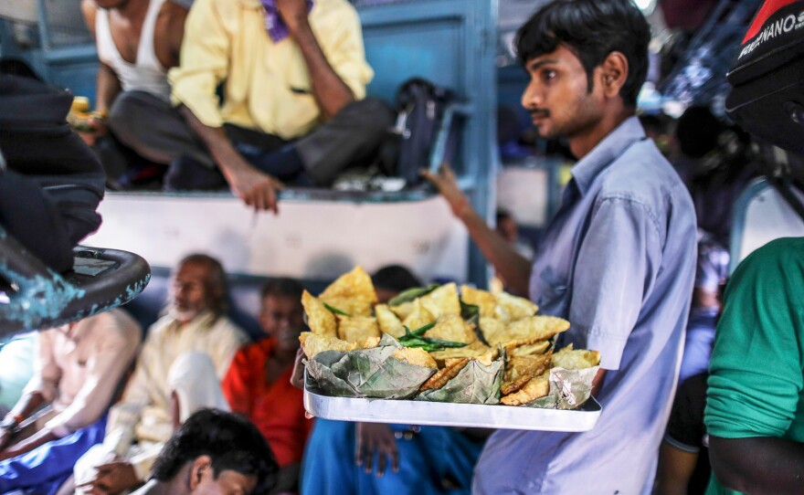 A vendor sells fried snacks on a train in northern India. Food vendors are a regular presence on most trains, jumping on and off trains at various stations, offering passengers a welcome snack break during their long journeys.