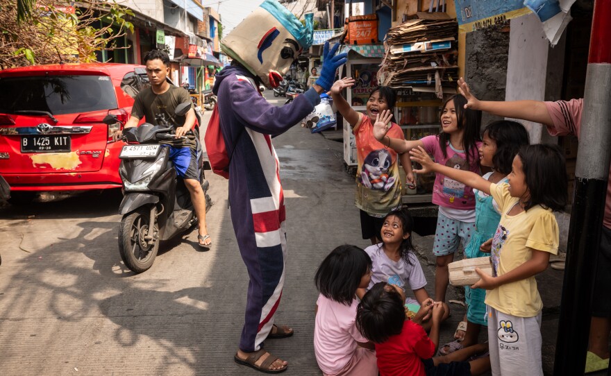 Indra, 28, who declined to provide his last name out of fear for his safety, dresses as a clown and plays music to earn some extra money in his neighborhood in Jakarta, Indonesia, on June 14, 2025. Indra, who previously worked on a commercial fishing vessel, recounted harrowing experiences at sea, where he said he witnessed abuses of his fellow cremates. Since returning home, he's refused to sign up for another job on a commercial fishing vessel, but says he has limited opportunities owing to the lack of a school degree. He currently works in a warehouse, packing boxes, and dresses as a clown to earn extra income.