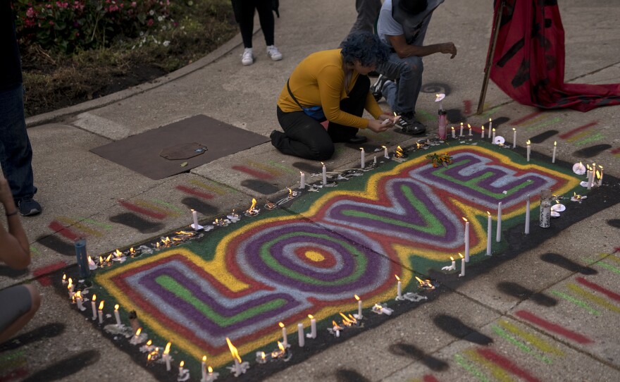 People place candles around an artwork that says "LOVE" as a group gathers in Kenosha.