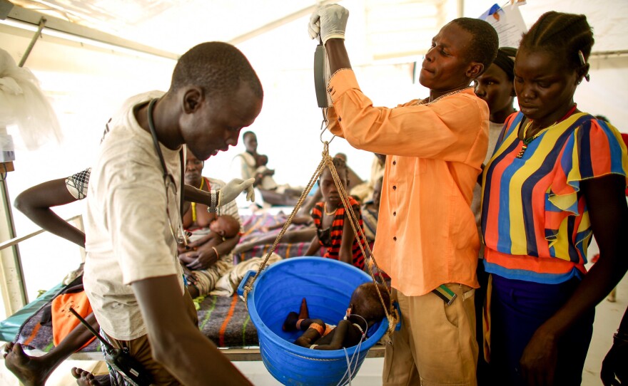 Local nurses at the MSF facility weigh a baby girl in a ward for malnourished children.