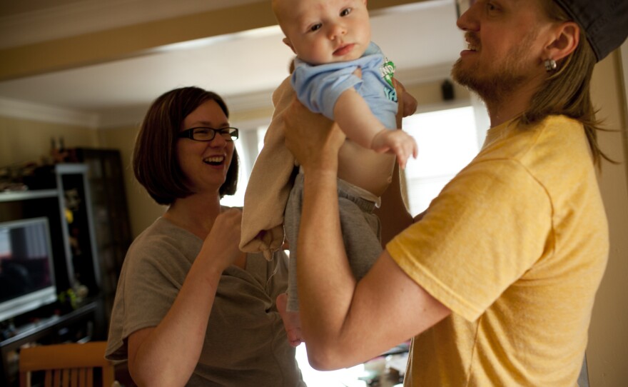 Dawn Heisey-Grove hands off Zane to Jonathan after a midday feeding. The couple were both working full time when Jonathan lost his job as a graphic designer two years ago.