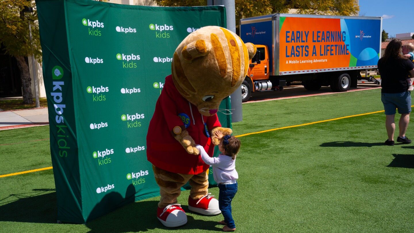 A young child greets Daniel Tiger at Be My Neighbor Day across the street from the KPBS station on Saturday, April 6 in San Diego, CA.