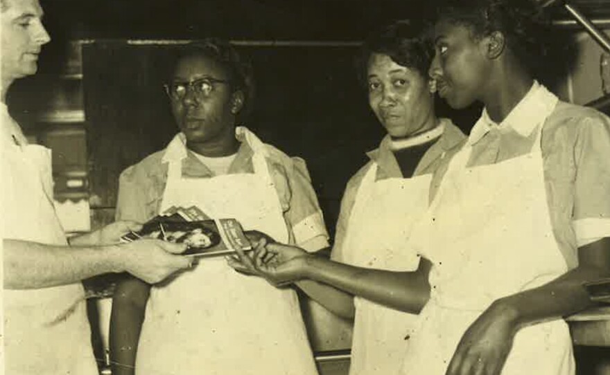 Ollie McClung Sr. hands religious tracts to employees. Most of Ollie's Barbecue's employees were black.