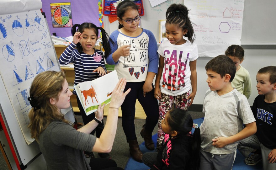 Teacher Elizabeth Carinder helps a group of her students present a book to their class.