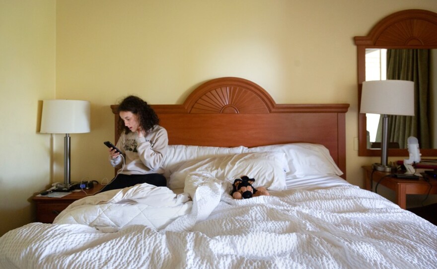Sarah Hamidi, 22, a senior at UCSB checks her phone in her hotel room on Nov. 17, 2021. Hamidi who applied for housing in hopes of getting an apartment was met with a waitlist, then given a temporary hotel room in Santa Barbara that she has occupied since Septempber of 2021.
