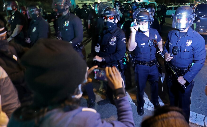 Protesters and police exchange words near a homeless encampment in Echo Park in Los Angeles on March 24, 2021.