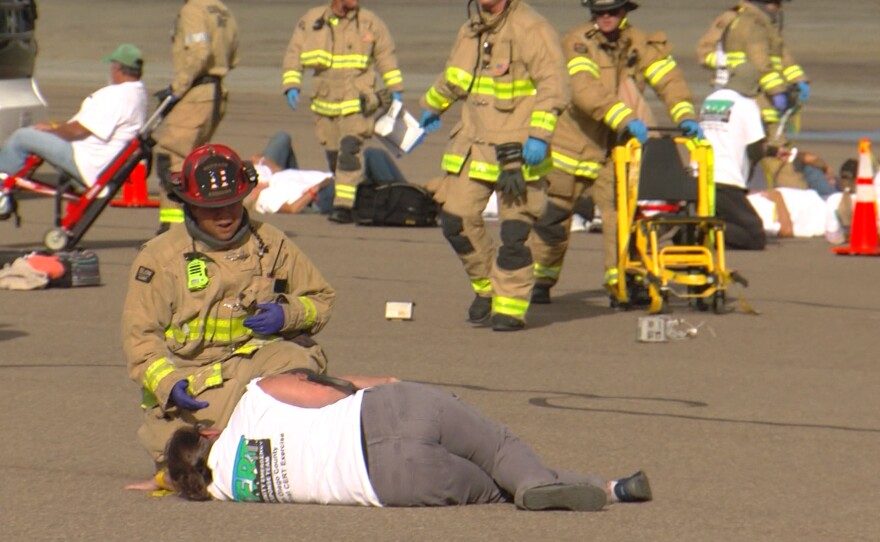 A firefighter tends to a volunteer portraying a victim during an emergency disaster drill at McClellan-Palomar Airport, Oct. 23, 2025.