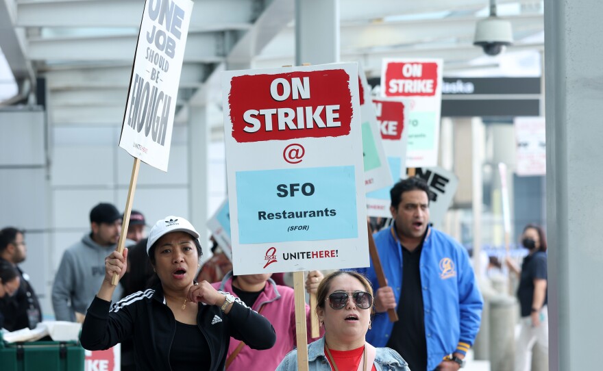 San Francisco International Airport food service workers carry signs as they strike outside of a terminal at the airport on September 26, 2022 in San Francisco, California.