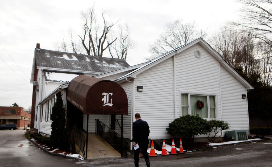 Funeral director Bob Lawler walks back into the Robert J. Lawler & Crosby Funeral Home after the burial at the Fairview Cemetery on Friday.