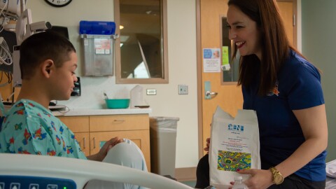 Elsa Morales-Roth (right), executive director of the Emilio Nares Foundation, hands a snack bag to a child recovering from chemoin this undated photo. 