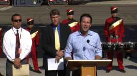 San Diego City Councilman Mark Kersey, along with Mt. Carmel High School band members and other city leaders, talks to reporters about a the city's new street repair machine, October 9, 2014.