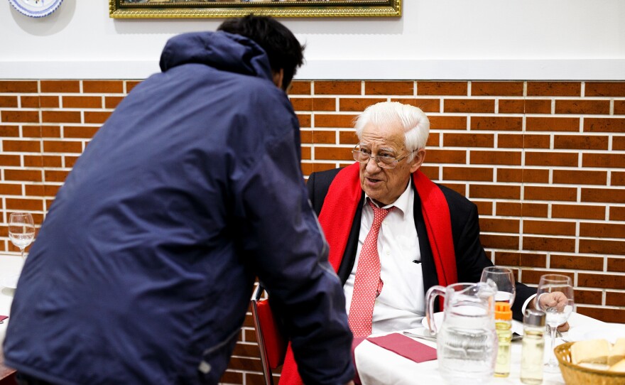 A dinner patron chats with Father Angel (right), who says that he wants homeless people to "eat with the same dignity as any other customer."