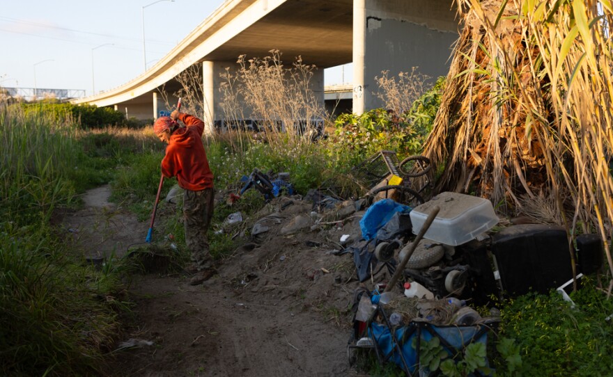 Ricky 'Stony' Jenkins cleans a trail leading to his tent on an island in the San Diego River, March 20. 2024.