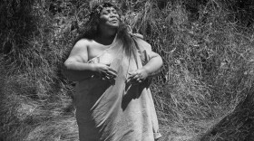 Edith Kanakaʻole chants in the koa forest of Kīpukapuaulu in Hawai'i Volcanoes National Park in 1977. She titled the photo "The Growth of Love is the Essence Within the Soul."
