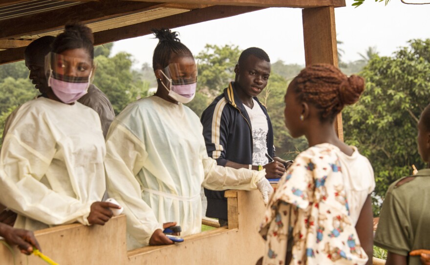 Health workers in Sierra Leone check travelers entering the country from Liberia.