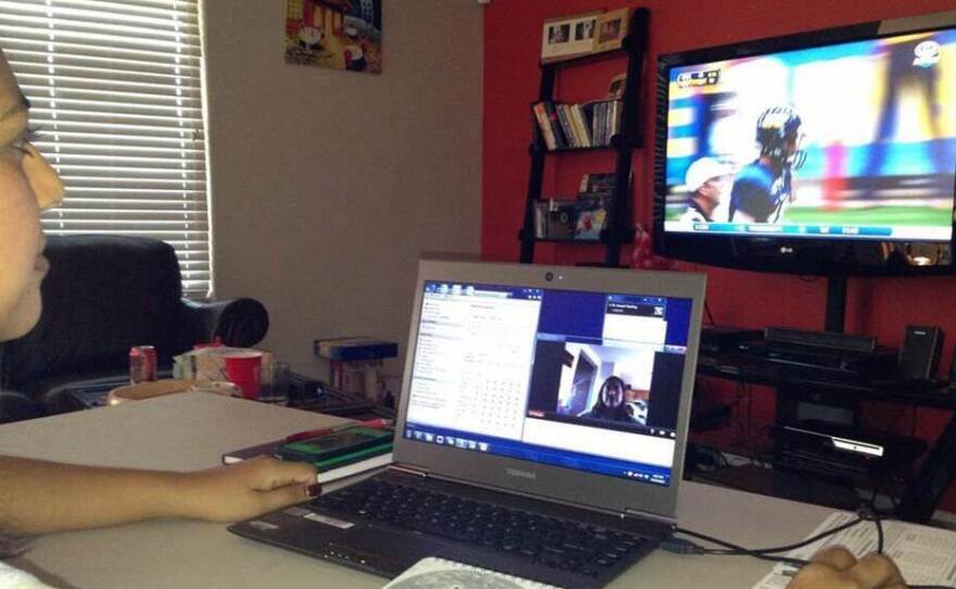 Dr. Amaal Starling, a neurologist from the Mayo Clinic in Arizona, watches a Northern Arizona University football game via both VGo and live television.