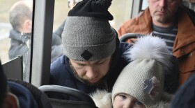 Refugees fleeing the military operation zone from the Mariupol area of Ukraine sit in a bus as they arrive at the border crossing in Veselo-Voznesenka, Russia, on Monday.