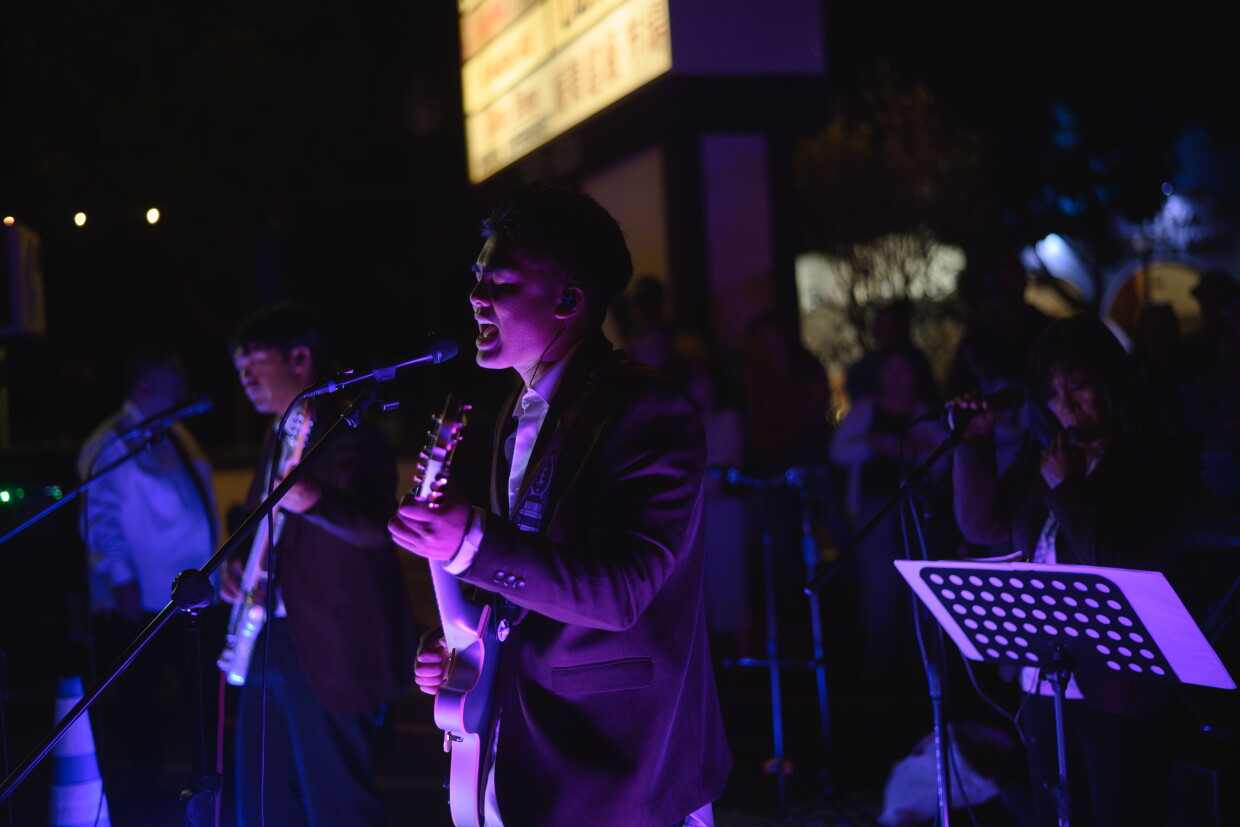 Membros da banda Together Again se apresentam sob o brilho das luzes roxas durante o mercado noturno em National City, Califórnia, em 11 de julho de 2026.